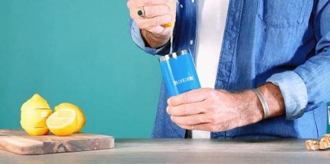 hands holding the shaker near a tray of lemons