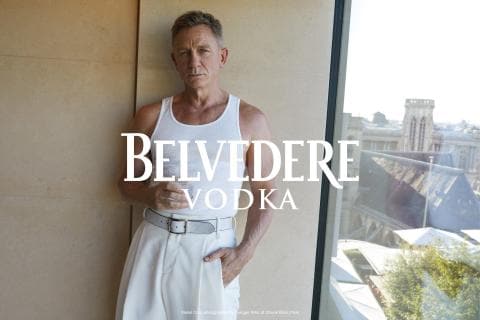 Daniel Craig leaning on a wall drinking Belvedere Vodka